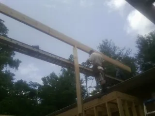 Carpenter setting a ridge beam over a new addition frame — Ice Dam Removal by Roofing Brothers in Whitsett