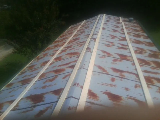 Rusted metal roof panels with new wood purlins before replacement — Storm Damage Roof Repair in Whitsett by Roofing Brothers