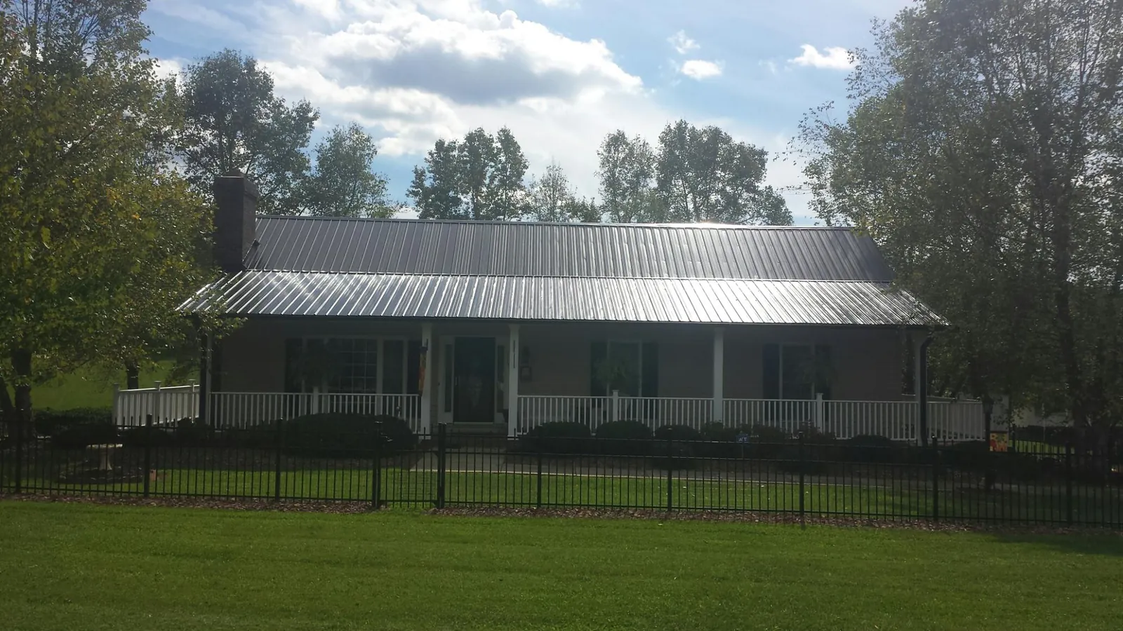 Gray metal roof on a brick ranch with a full width front porch — Gutter Guard Installation work by our crew in Whitsett